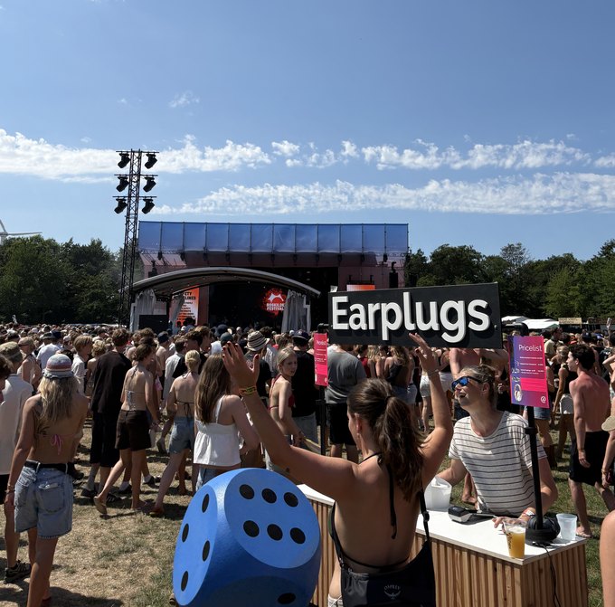 Earproof earplug point at Roskilde Festival, with the crowd and main stage behind it